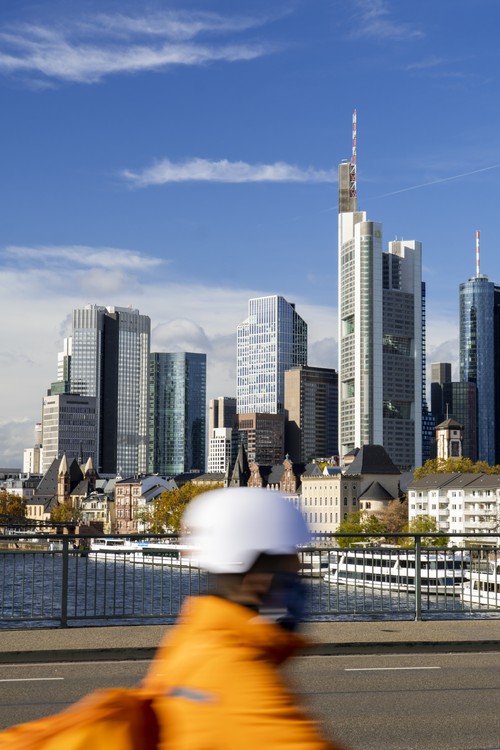 Hochhäuser, Skyline Frankfurt 'Mainhattan', von Alte Brücke. Vermutlich Lieferservice-Fahrer mit Maske. Main. Lieferando, Lieferdienst