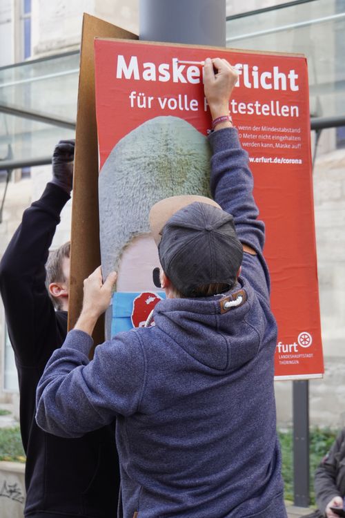 Maskenpflicht für volle Haltestellen. Plakat, Maske, Herz. Beim Aufhang